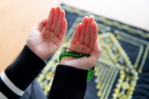 A Muslim woman is doing Istikhara dua while sitting on a prayer mat