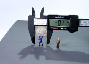 A digital caliper measuring a one euro coin with tiny figurines of a person pointing and another observing, symbolizing the precise evaluation and balancing of financial transactions in relation to the blog 'Riba (Interest) in Islam: 5 Key Insights to Navigate Financial Transactions'.