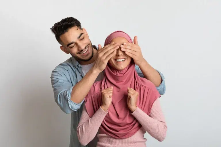 A playful moment between a Muslim couple, with the husband gently covering his wife's eyes, symbolizing love, intimacy, and mutual affection within the framework of Islamic teachings on relationships.