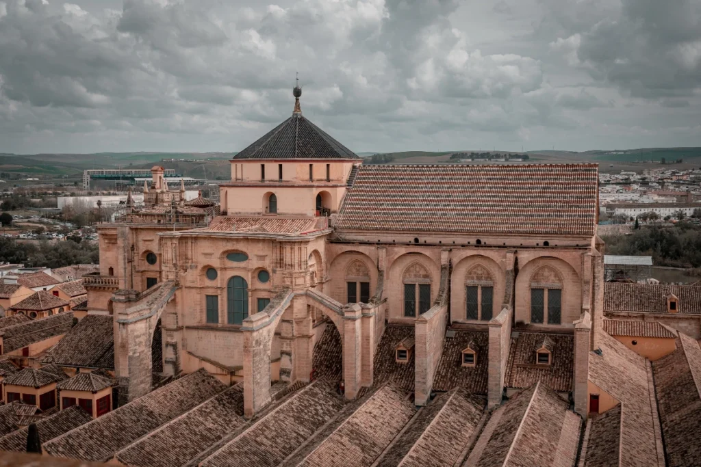 Aerial view of the Great Mosque of Córdoba in Spain, featuring its unique blend of Islamic and Gothic architectural elements, with its tiled roofs and intricate arches, symbolizing the legacy of Andalusian Islamic architecture.