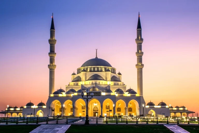 A stunning mosque at sunset with illuminated domes and minarets, showcasing the elegance and grandeur of Islamic architecture.