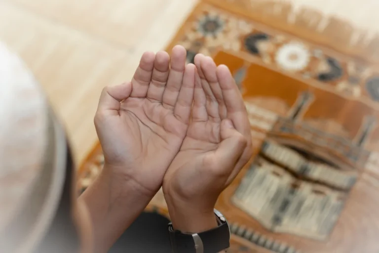 Person raising hands in supplication on a prayer mat, making Dua for Pain relief in Islam.