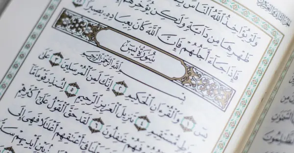 Close-up view of Surah Yaseen from the Quran, beautifully illuminated with intricate design and Arabic calligraphy.