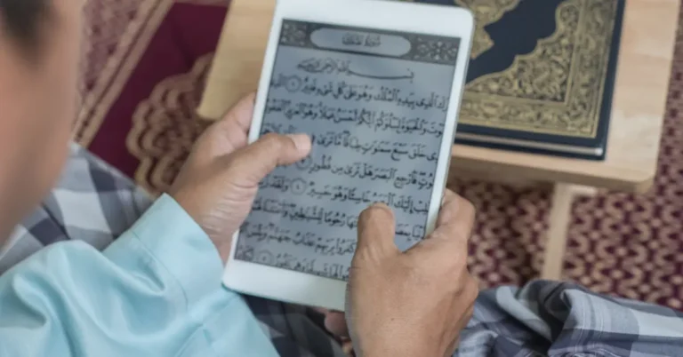 A Muslim man studying the Quran on a tablet at home, symbolizing flexible learning through the Best Online Quran Academies in the UK.